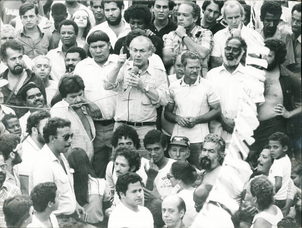 Leonel Brizola discursa ao lado de Juruna. Abdias Nascimento aparece no canto direito da foto